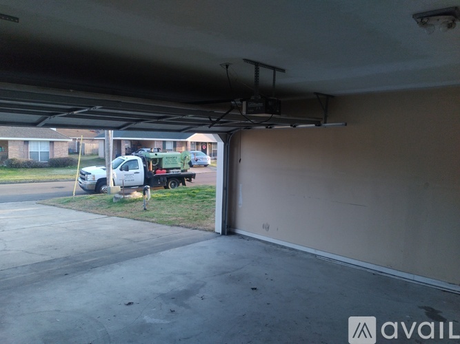 A white truck is parked in a driveway under a garage.