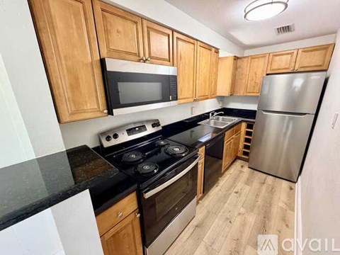 A kitchen with wooden cabinets and black countertops.