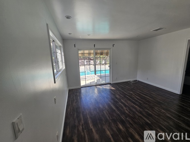 A room with wooden floors and a sliding glass door leading to a balcony.