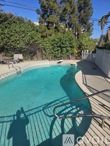 A pool surrounded by trees and a fence.
