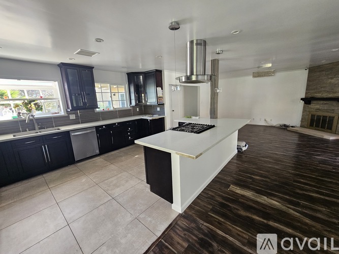 A kitchen with dark wood floors and a white island with a black countertop.