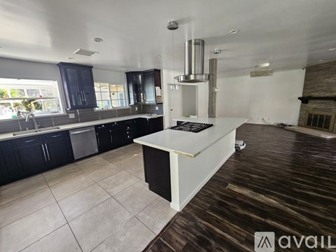 A kitchen with dark wood floors and a white island with a black countertop.