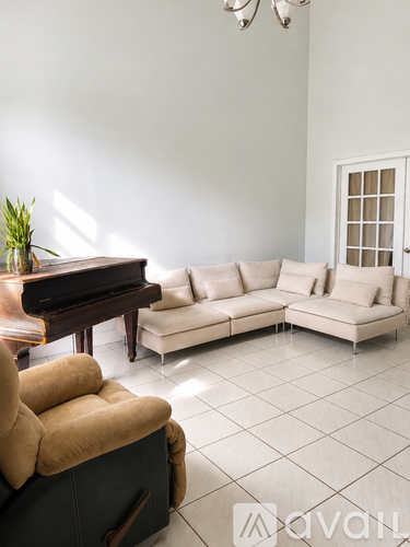 A living room with a piano, a couch, and a chair.