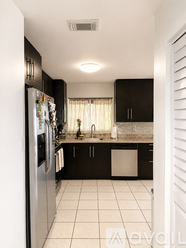 A kitchen with black cabinets and a white refrigerator.