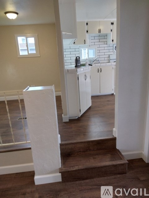 A kitchen with white cabinets and a wooden floor.