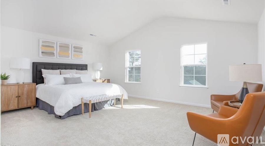 A bedroom with a large bed and a chair.