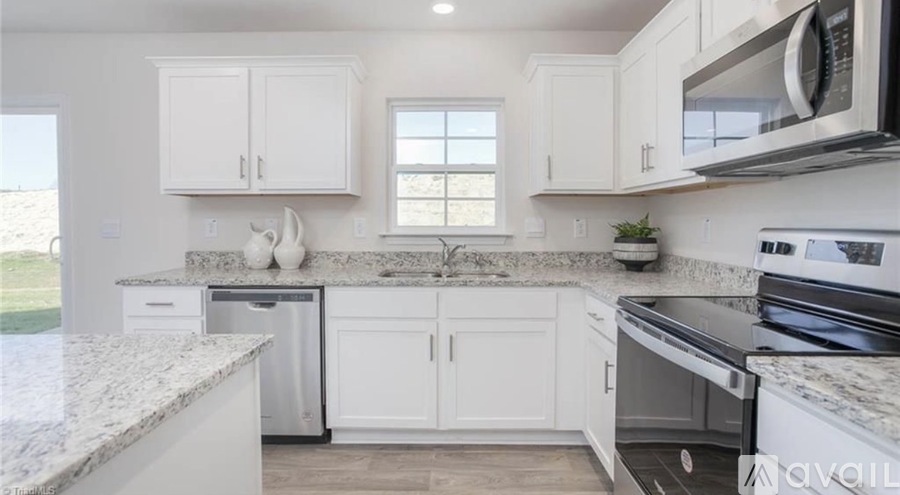 A kitchen with white cabinets and granite countertops.