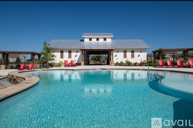 A large swimming pool in front of a house with a metal roof.