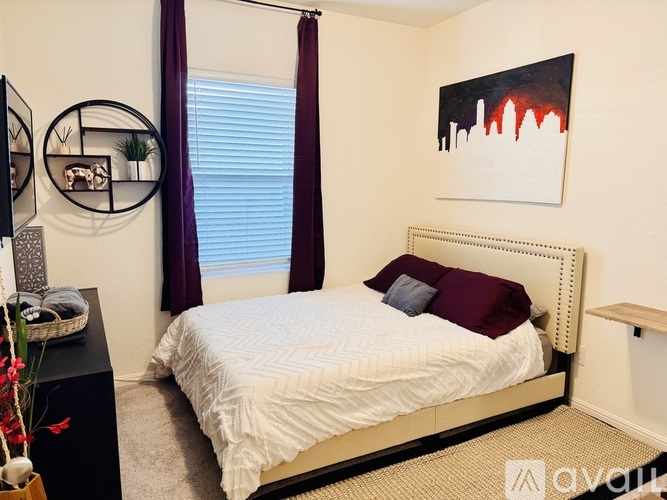 A bedroom with a white bed and a painting on the wall.