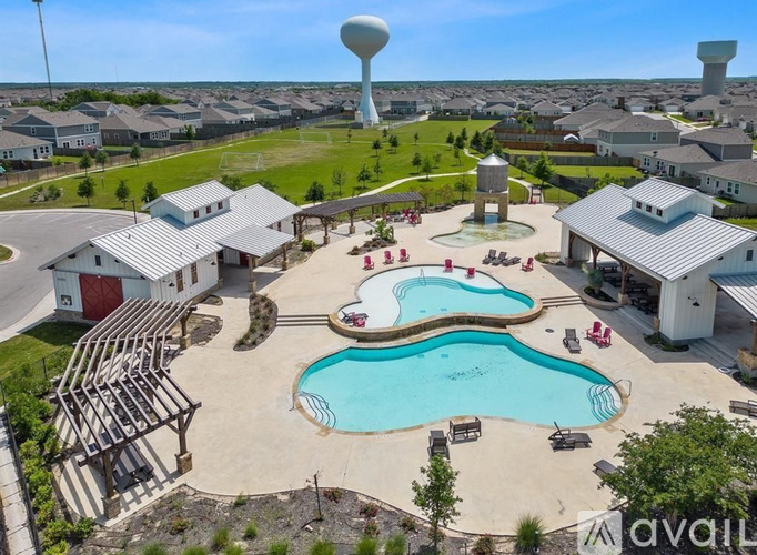 A large water tower stands in the distance behind a small pool and pavilion.