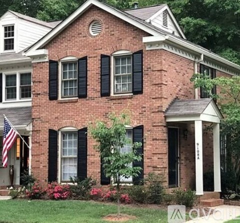 A red brick house with black shutters and a white porch.