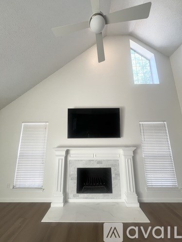 A living room with a fireplace and a television mounted above it.