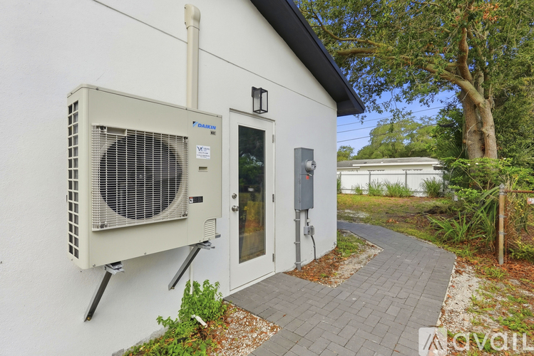 A white building with a large fan on the side and a door with a glass window.
