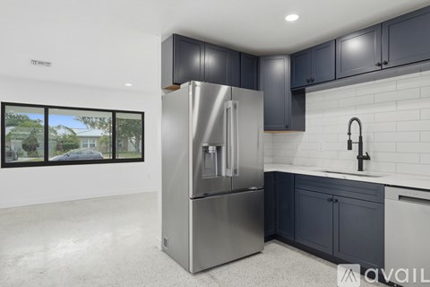 A modern kitchen with a stainless steel refrigerator and dark grey cabinets.