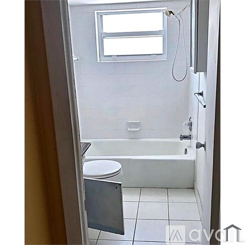 A small bathroom with a toilet, tub, and window.