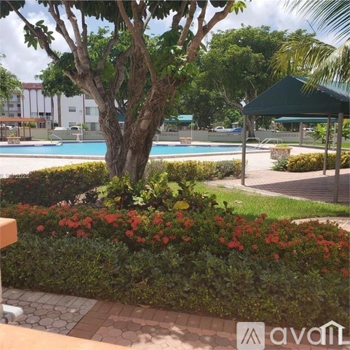A pool surrounded by greenery and a tree.