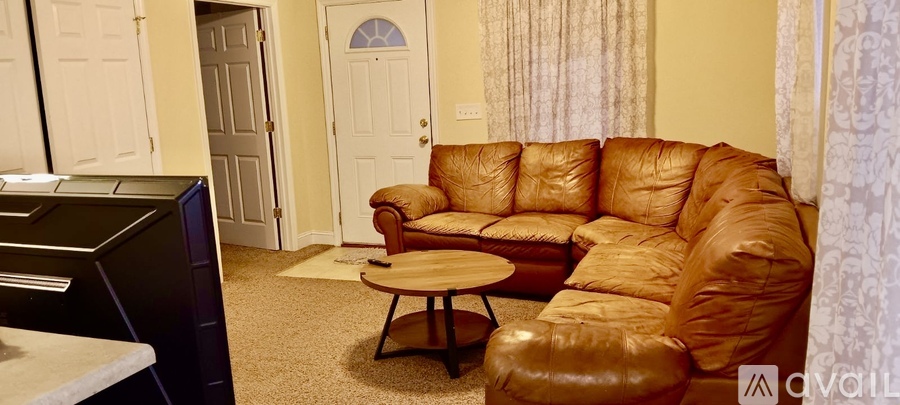 A brown leather couch sits in a living room with a small table in front of it.