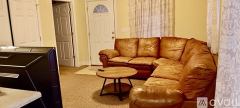 A brown leather couch sits in a living room with a small table in front of it.