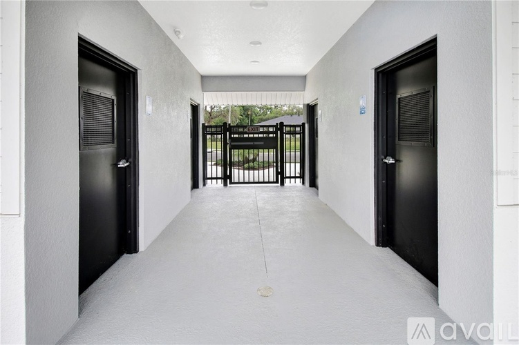 A long hallway with black doors and a white floor.