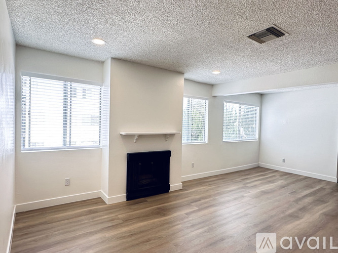 A living room with a fireplace and two windows.