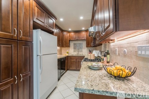 A kitchen with brown cabinets and a marble countertop.