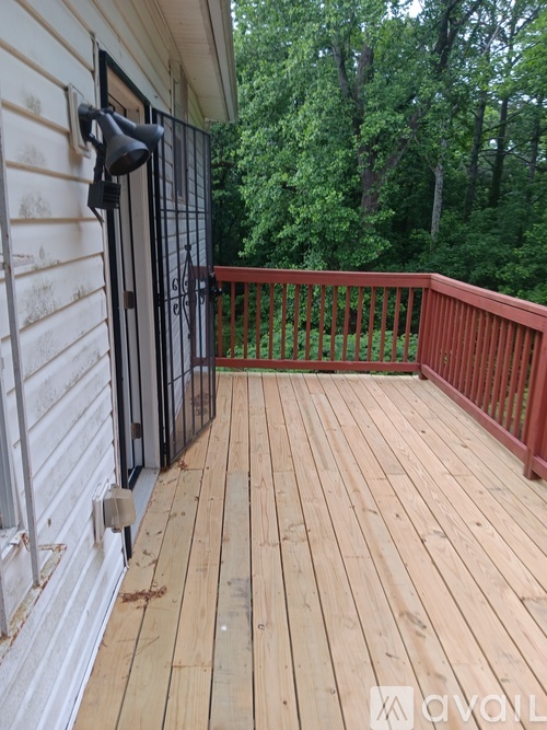A wooden deck with a black gate and a red railing.