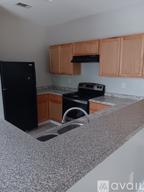 A kitchen with a black fridge and an oven with a black stove top.