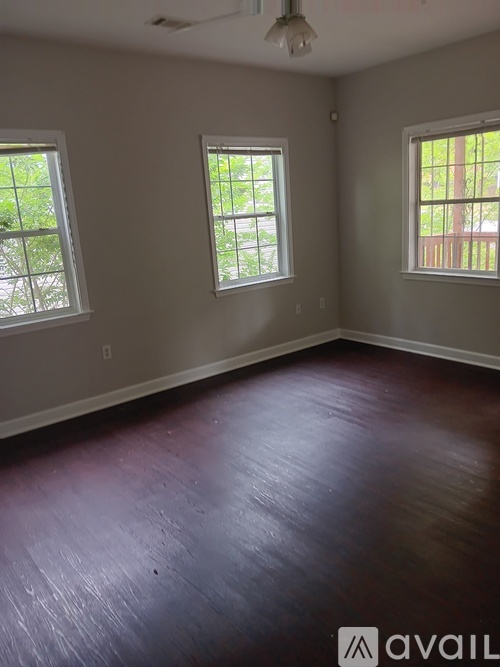 A room with wooden floors and three windows.