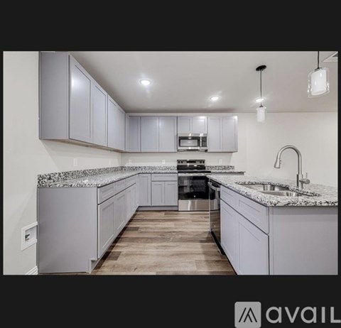 A modern kitchen with a granite countertop and wooden flooring.