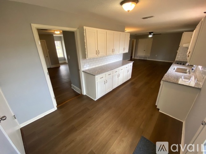 A kitchen with white cabinets and a wooden floor.