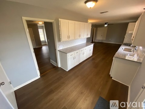 A kitchen with white cabinets and a wooden floor.