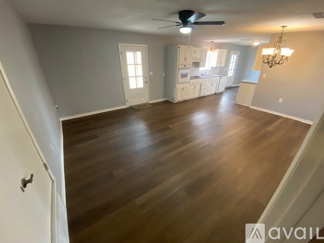 A spacious room with wooden flooring and a ceiling fan.