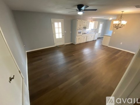 A spacious room with wooden flooring and a ceiling fan.