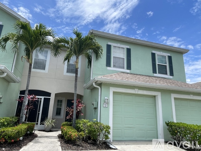 A two-story house with a garage and palm trees in front.