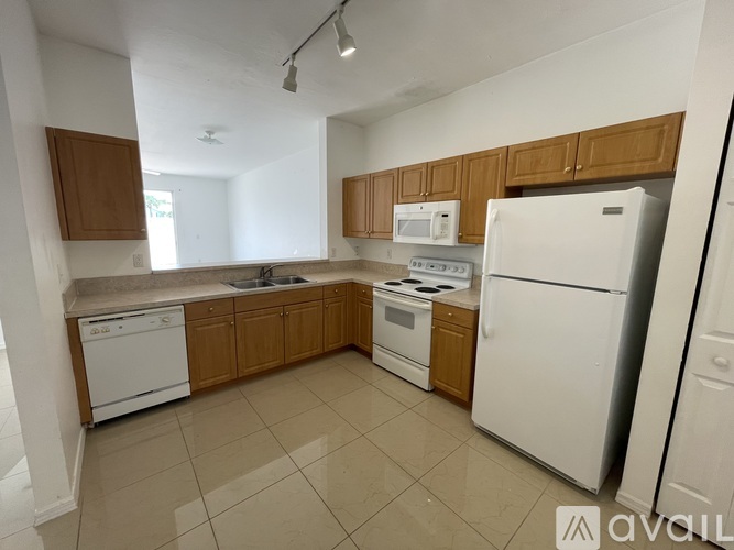A kitchen with white appliances and wooden cabinets.