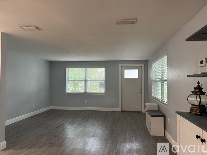 A spacious room with a window, door, and a bench.