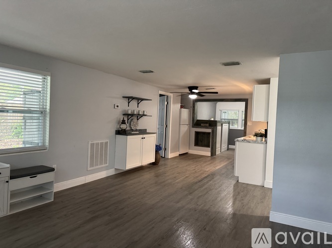 A spacious living room with a kitchen in the background.