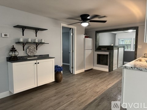 A kitchen with a ceiling fan and a counter with a basket of blue flowers.