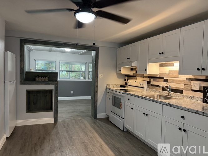 A kitchen with a refrigerator, cabinets, and a ceiling fan.