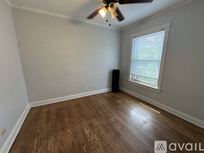A room with a ceiling fan and a window with a view of trees outside.