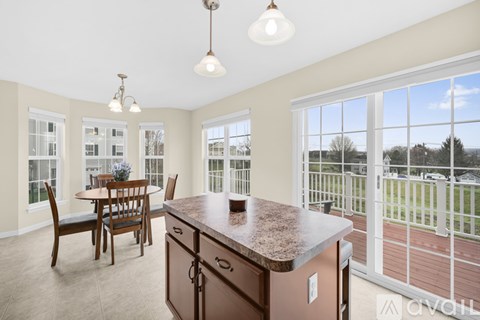 A kitchen with a table and chairs and a balcony with a view of the outside.