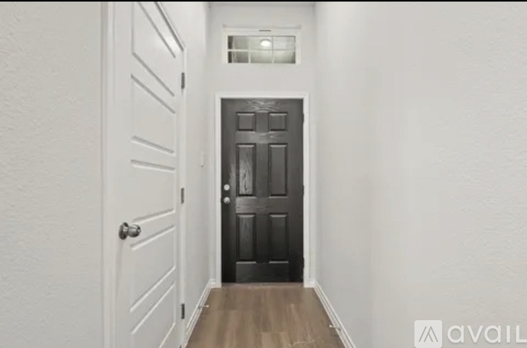 A hallway with a black door and a white door on the left.