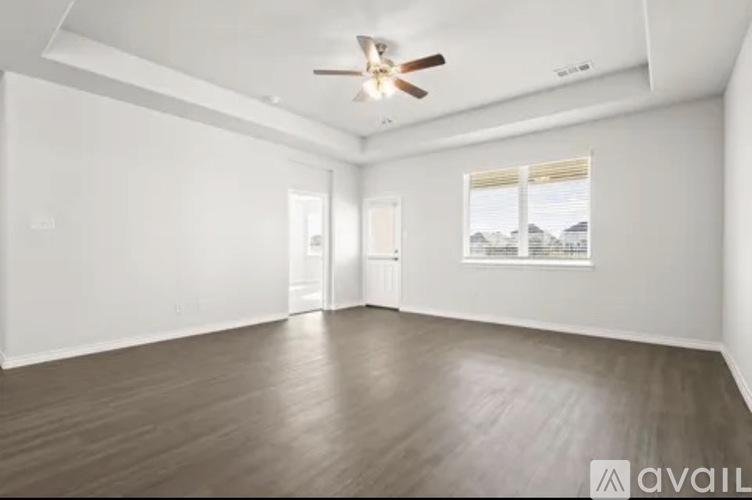 A spacious room with a ceiling fan and wooden flooring.