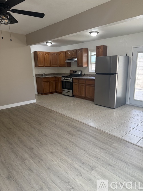 A kitchen with a refrigerator, cabinets, and a ceiling fan.