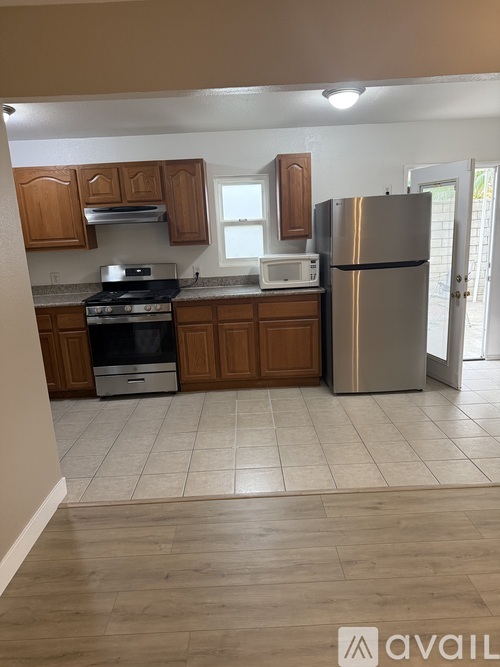 A kitchen with wooden cabinets and a stainless steel refrigerator.