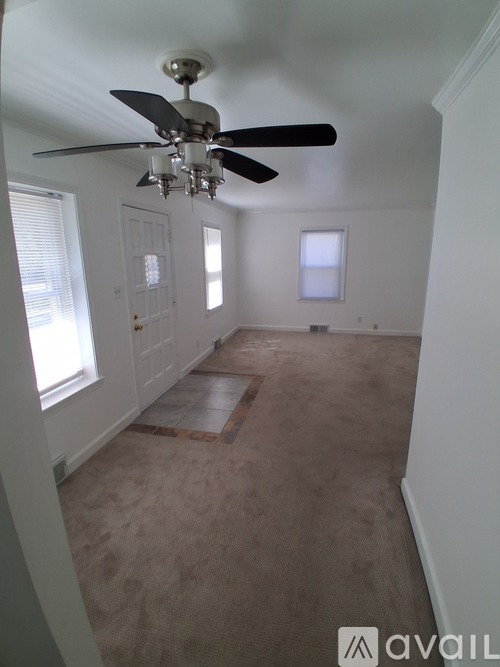 A room with a ceiling fan and carpeted floor.