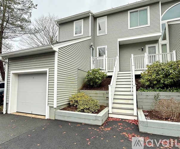 A grey house with a white garage door and a white staircase leading to the entrance.