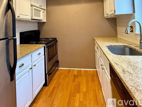 A kitchen with white cabinets and a black fridge.