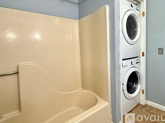 A white bathtub in a bathroom with a washing machine in the background.
