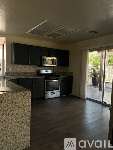 A kitchen with black cabinets and a granite countertop.